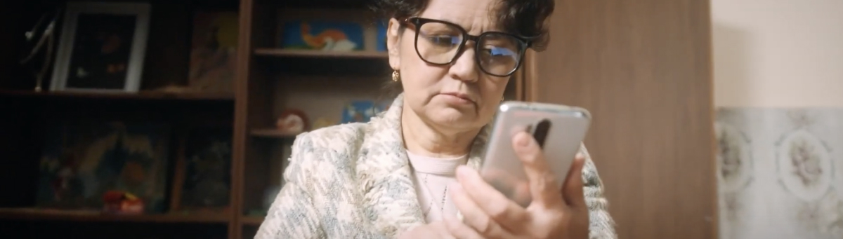 Женщина в очках смотрит в телефон который держит в руке